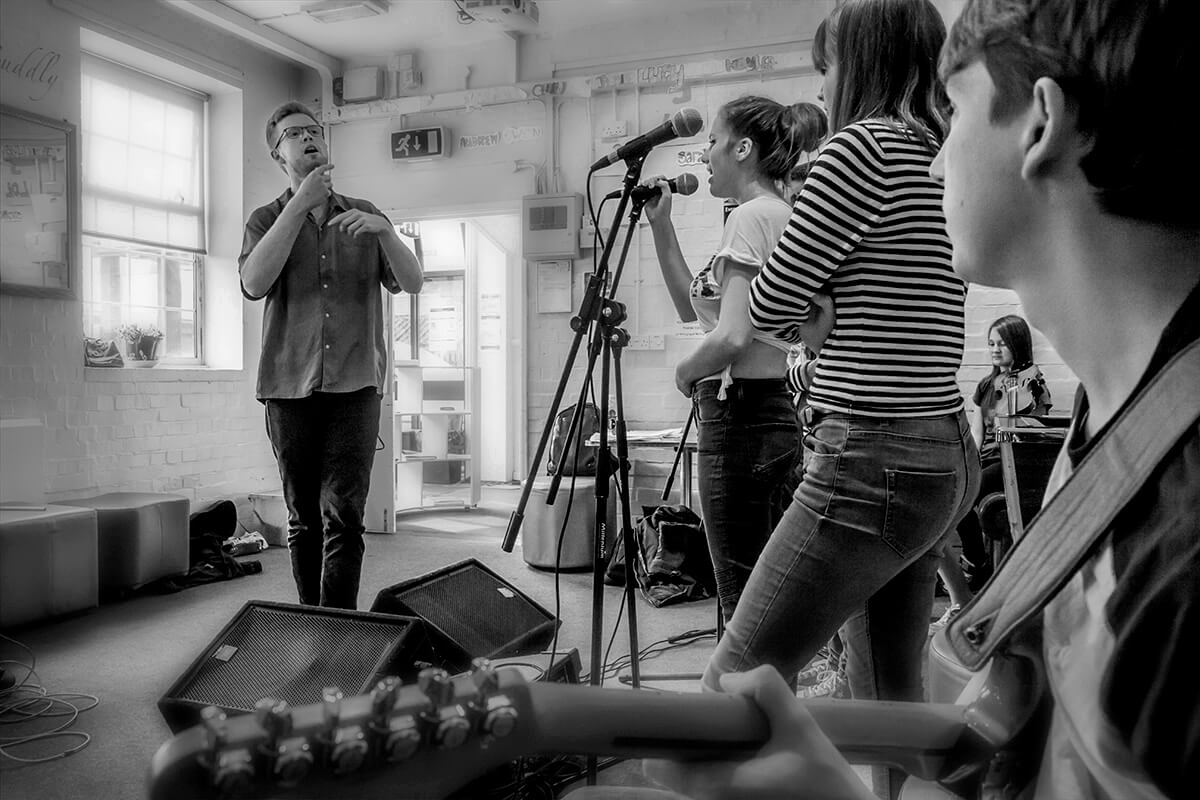 Monochrome photo of Matt Hartnell facilitating a youth music workshop